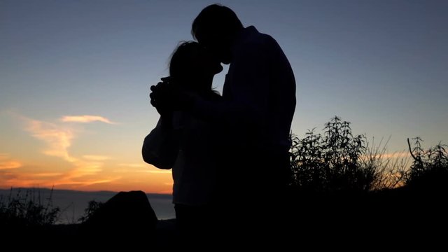 Silhouette of couple dancing and kissing during sunset, super slow motionow
