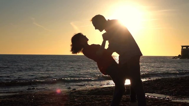 Silhouette of couple dancing during sunset, super slow motion

