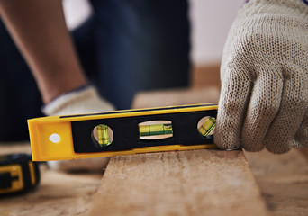 Woodworking. Male joiner in gloves measuring timber with plane on the floor.