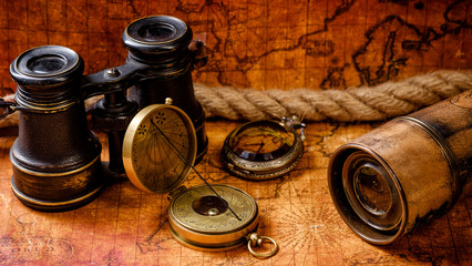 Old vintage retro compass and spyglass on ancient world map