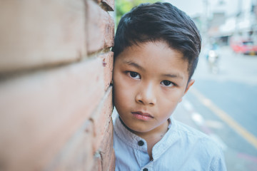 scared and alone, young Asian child who is at high risk of being bullied, trafficked and abused, selective focus