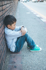 scared and alone, young Asian child who is at high risk of being bullied, trafficked and abused, selective focus