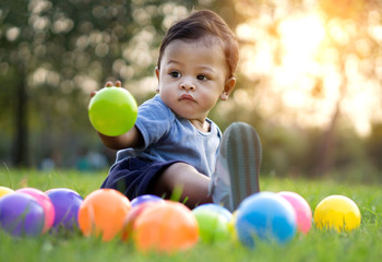 Cute asian baby playing colorful ball in green grass - Powered by Adobe