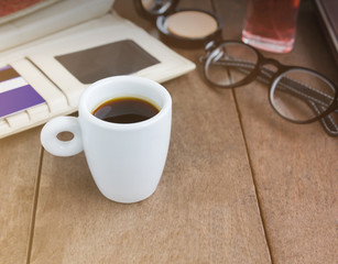 White cup hot black coffee on wood table with working women thin
