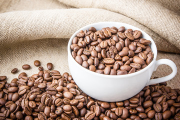 White mug filled with coffee seeds.