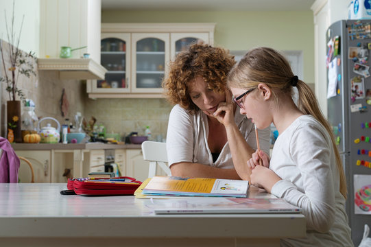 Mother helping daughter with her homework at the table in the dinning room.