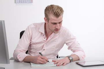 Junger Mann am Schreibtisch mit Formularen und Pad