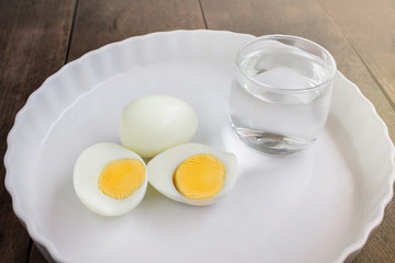 Boil eggs on white plate with glass of water in morning meal fee