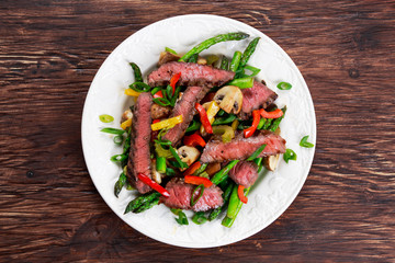 Grilled steak with stir-fried vegetables on plate.