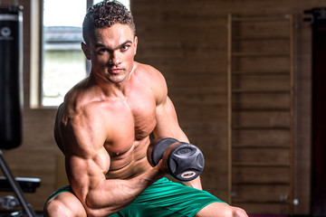 Muscular bodybuilder guy doing exercises with dumbbells
