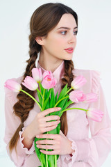 Beautiful young woman holding a bunch of delicate spring pink tulips in front of her