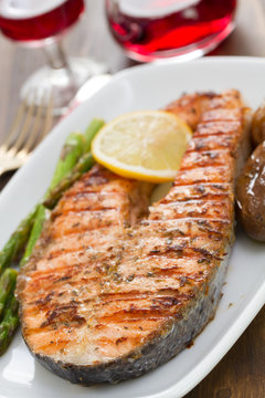 grilled fish with lemon and vegetables on white dish