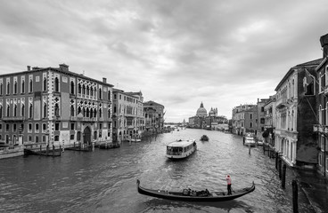 Beautiful view of traditional Gondola and boats on Canal Grande with Basilica di Santa Maria della Salute church in background at a cloudy day, Venice (Venezia), Italy, Europe, black and white

