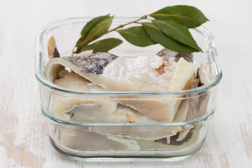 salted cod fish in water in glass dish