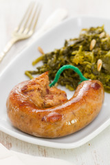traditional portuguese smoked sausage with turnip greens on white plate