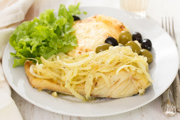 cod fish with onion, mashed potato and salad on white plate and glass of wine