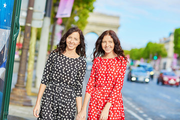 Naklejka premium Beautiful twin sisters in front of Arc de Triomphe