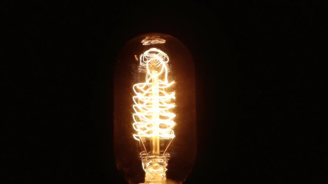 A retro vintage Edison-like light bulb being turned on and off. Close-up shot.