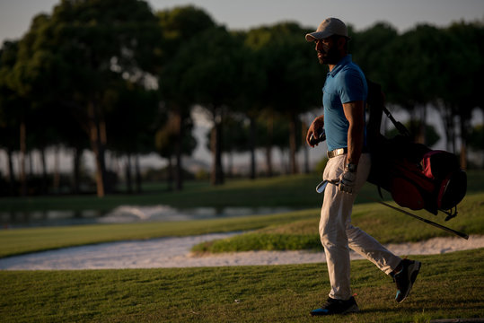 golfer walking and carrying golf bag at beautiful sunset
