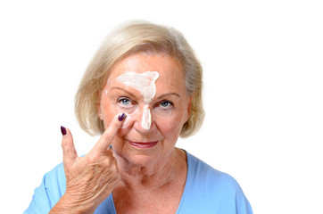 Attractive blond senior lady applying cosmetics