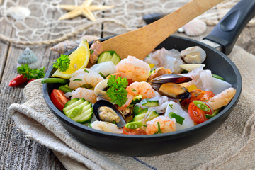 Gemischte Meeresfrüchte und knackiges Gemüse vor der Zubereitung in einer Pfanne -  Food combining, mixed seafood and fresh vegetables before cooking in a frying pan