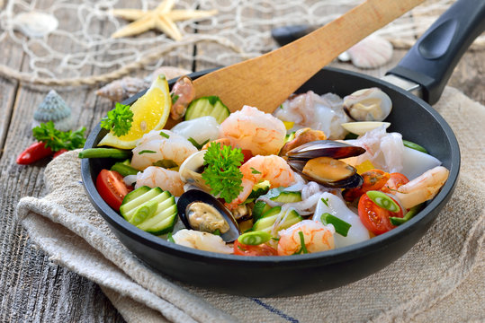 Gemischte Meeresfr&uuml;chte und knackiges Gem&uuml;se vor der Zubereitung in einer Pfanne -  Food combining, mixed seafood and fresh vegetables before cooking in a frying pan