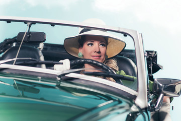 Smiling retro 60s woman with driving sports car.