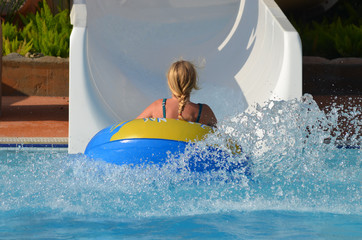 Blonde girl in swim ring going down water slides at water park Kusadasi, Turkish Riviera, Turkey