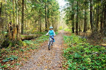 Obraz premium Little girl riding on bicycle in the forest
