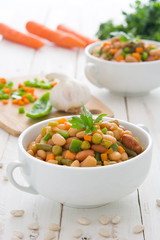 White beans with vegetables on white wood

