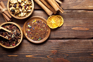 Various leaves of tea and spices on wooden background