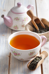 Cup of tea, teapot and dried tea leaves