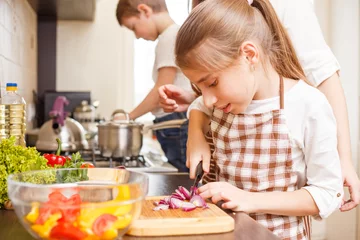Photo sur Plexiglas Cuisinier Fond de cuisine familiale. Adolescente coupant l& 39 oignon