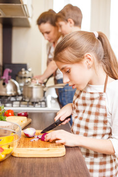 Family cooking background. Teen girl cutting onion
