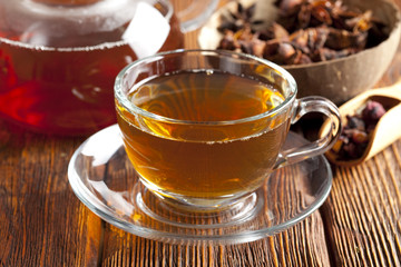Assorted tea leaves, cup of tea and teapot on wood