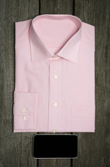 Pink shirt and mobile on wooden background