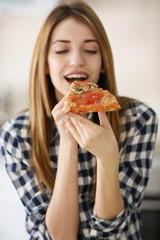 Happy young woman eating slice of hot pizza, close up