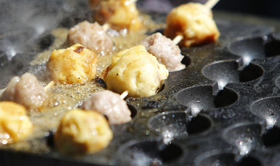 Quail eggs on wood stick sizzling in specialized fry pan