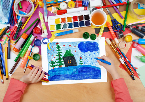 Child Drawing Christmas Night In Forest With House , Top View Hands With Pencil Painting Picture On Paper, Artwork Workplace