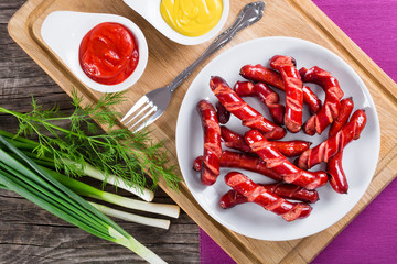 Grilled sausages on a white dish, top view