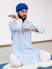  man in a turban sitting on the mat doing mudra