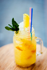 Preparation of the lemonade drink with tubes. Lemonade in the jug with lemons with mint on the table