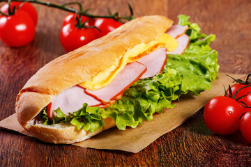 Sandwich from fresh baguette on wooden background