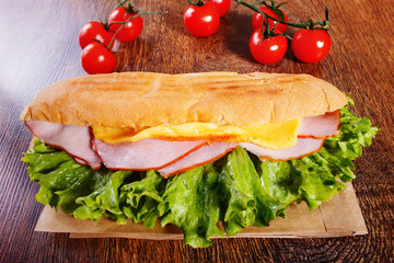 Sandwich from fresh baguette on wooden background