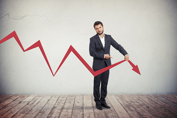 Businessman pointing to red graph arrow down.