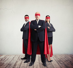 Two businessmen and businesswoman in superhero costume