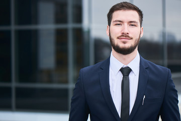 Portrait of young man in suit on the background of the building with a glass facade