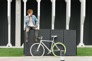 Handsome young man with mobile phone and fixed gear bicycle.