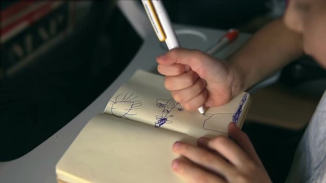 cild draws a plane sitting on the board of plane