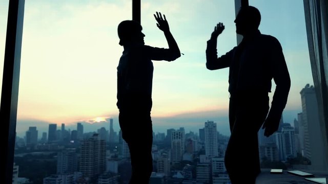 Successful business people giving high five in office, slow motion
